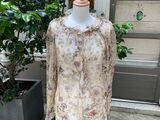 une robe de mannequin posée sur un pied de mannequin, à côté d'une plante en pot