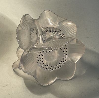 a silver flower shaped object sitting on a white surface