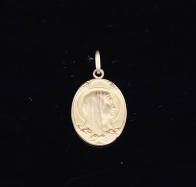 une petite médaille en or représentant une femme de profil sur fond noir