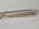 a silver spoon with a handle on a white surface