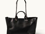 a black leather tote bag with chain handles on a white background