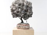une sculpture représentant un arbre posée sur un bloc de bois