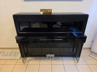 a black piano in the corner of a room with a picture on the wall behind it