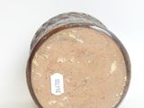 a brown vase sitting on a white surface with a tag on it