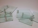 two glass tables with metal legs and a glass shelf