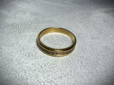 a close up of a gold wedding ring on a white surface
