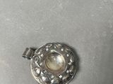 silver plated pendant with a pearl in the middle of it on a table