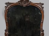 un miroir au cadre en bois richement sculpté, posé sur une surface blanche