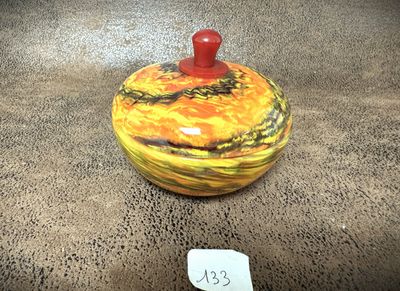 a yellow and red jar with a red lid sitting on a table