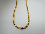a close up of a gold necklace on a white surface