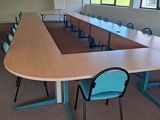 des tables et des chaises dans une grande salle de conférence, avec un écran de projection en arrière-plan