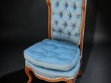 une image représentant une chaise dont l'assise est recouverte d'un tissu bleu, dans une pièce sombre