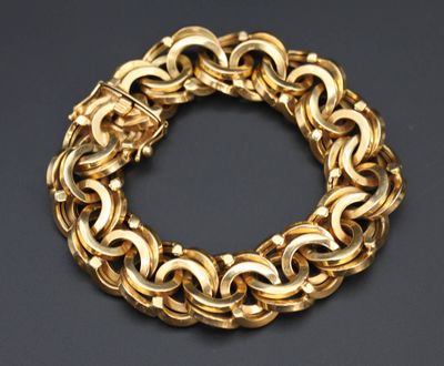 gros plan d'un bracelet en chaîne en or sur une surface noire