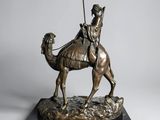 bronze statue of a man riding a camel with a spear in his hand