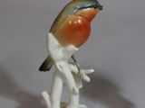 two figurines of birds sitting on a tree branch