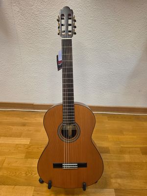 an acoustic guitar on a stand on a hard wood floor