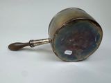 an old metal cup with a handle on a white surface