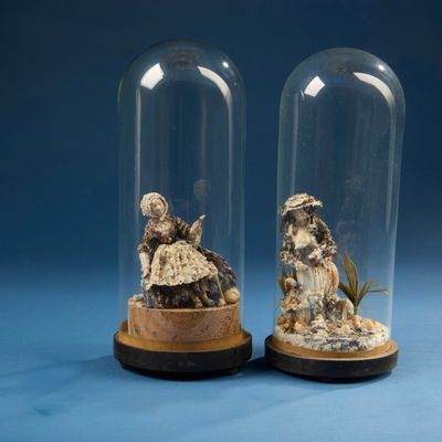 deux cloches en verre contenant des figurines représentant des personnes