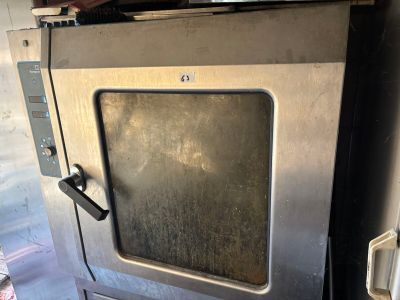 un four en métal avec une porte vitrée, installé dans un garage