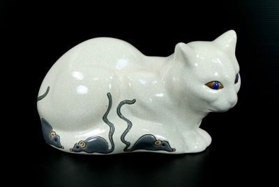 une figurine de chat blanc posée sur une surface noire