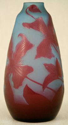un vase bleu orné de fleurs rouges, posé sur un fond blanc