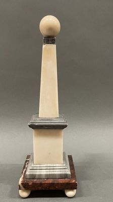 a white and black statue with a wooden base and a ball on top of it