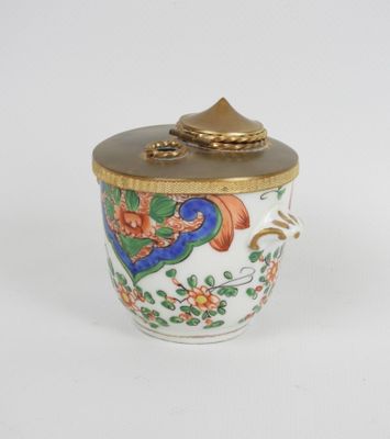 un petit vase avec un couvercle posé sur une surface blanche