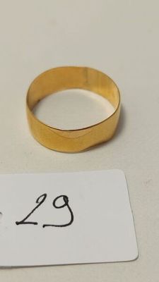 une bague en or et une étiquette posées sur une table blanche