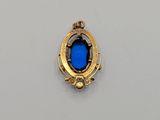 a gold pendant with a blue stone in the center