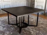 La table est en métal et possède un plateau noir.