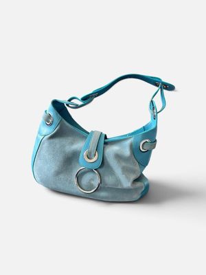 sac à main en cuir bleu sur fond blanc, avec des découpes sur la bandoulière