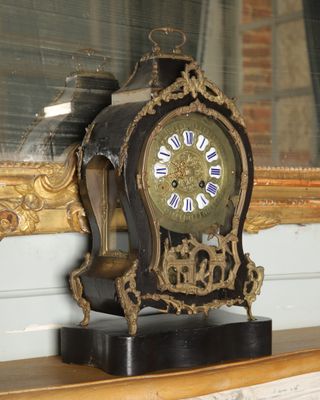 a clock sitting on a shelf in front of a mirror