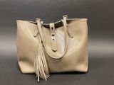 a beige leather tote bag with a tassel on the handle