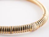 a close up of a gold and diamond bracelet on a white surface