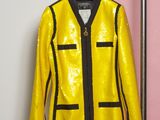 une veste jaune accrochée à un porte-vêtements devant un mur rose