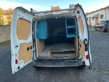 une camionnette blanche dont les portes sont ouvertes, garée sur un parking