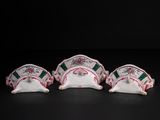 three white and green tea cups and saucers sitting on a black surface