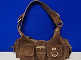 a brown sued purse with two buckles on a white surface