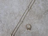 un gros plan d'un collier et d'une paire de boucles d'oreilles posés sur une surface en béton
