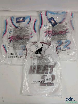 trois sacs de t-shirts sont emballés dans du plastique sur une table