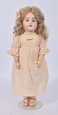 an antique doll with blonde hair and blue eyes standing on a white surface