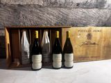 three bottles of wine in a wooden box on a table