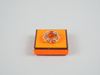 une boîte orange surmontée d'un anneau, posée sur une surface blanche