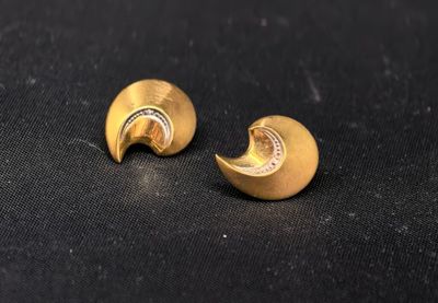 une paire de boucles d'oreilles en or sur une surface noire