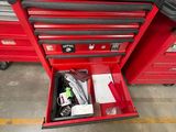 une boîte à outils rouge contenant des outils, dans un garage