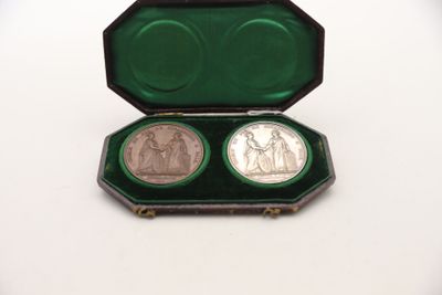 deux pièces d'argent dans un étui vert posé sur une surface blanche