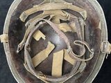 an old military helmet with a leather strap and a metal buckle