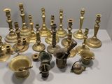 many different types of brass candles on a white table