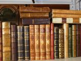 de nombreux livres anciens sur une étagère à côté d'une horloge