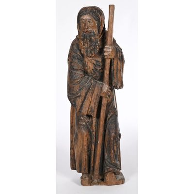 an old wooden statue of a man holding a staff